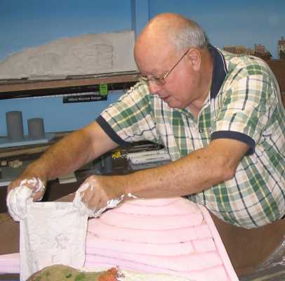 Rich Cutler drapes plaster cloth over a foam base to form a mountain on the layout of APN