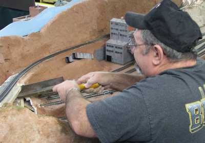 Charlie Richmond cutting out roadbed to make way for a bridge on the APN layout